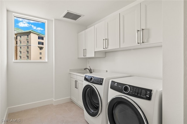 washroom featuring visible vents, cabinet space, a sink, washer and dryer, and baseboards