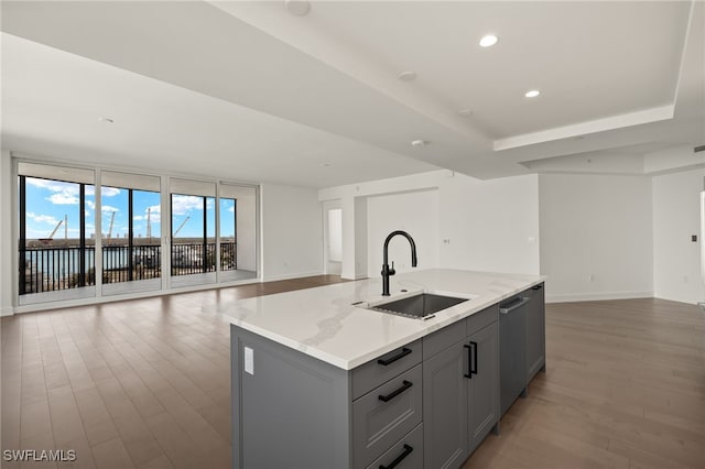 kitchen with open floor plan, wood finished floors, a sink, gray cabinets, and stainless steel dishwasher