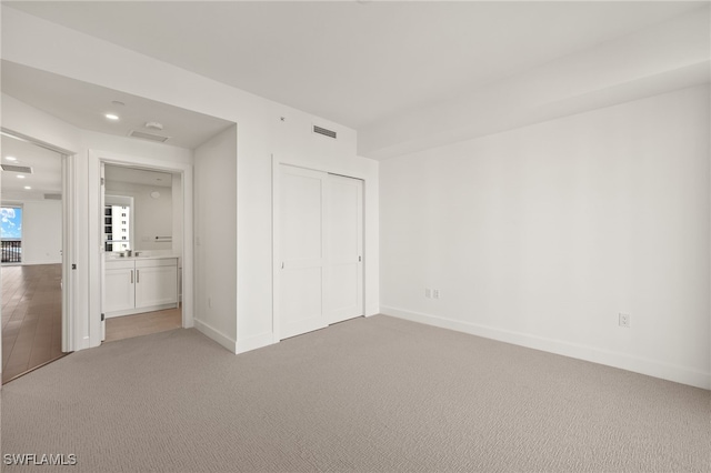 unfurnished bedroom featuring light colored carpet, a closet, visible vents, and baseboards