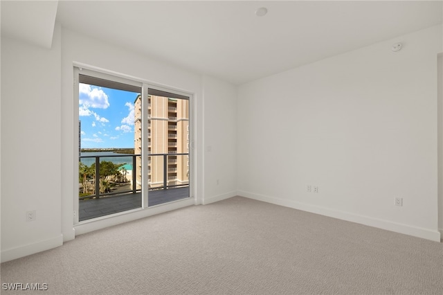 spare room featuring a water view, carpet flooring, and baseboards