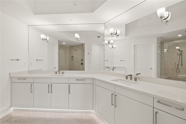 bathroom with double vanity, a shower stall, a sink, and tile patterned floors