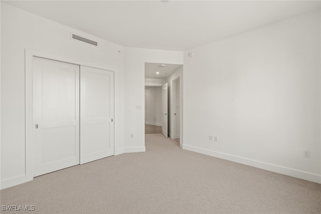 unfurnished bedroom with baseboards, a closet, visible vents, and light colored carpet