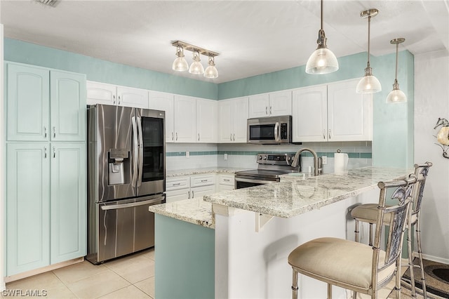 kitchen with stainless steel appliances, backsplash, a kitchen bar, decorative light fixtures, and white cabinets