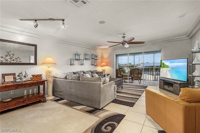 living room with ceiling fan, crown molding, rail lighting, light tile flooring, and a fireplace