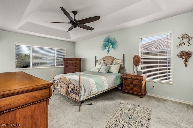 bedroom featuring ceiling fan, a raised ceiling, and light carpet