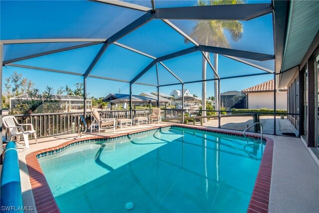 view of pool with glass enclosure and a patio area