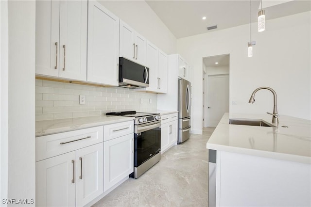 kitchen with light stone countertops, appliances with stainless steel finishes, sink, white cabinetry, and hanging light fixtures