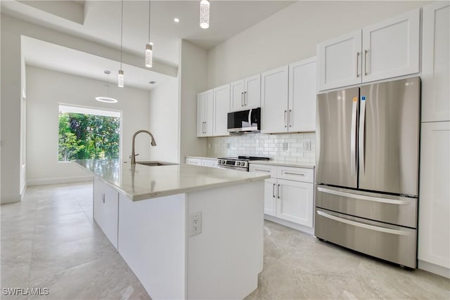 kitchen featuring sink, stainless steel appliances, pendant lighting, a center island with sink, and white cabinets