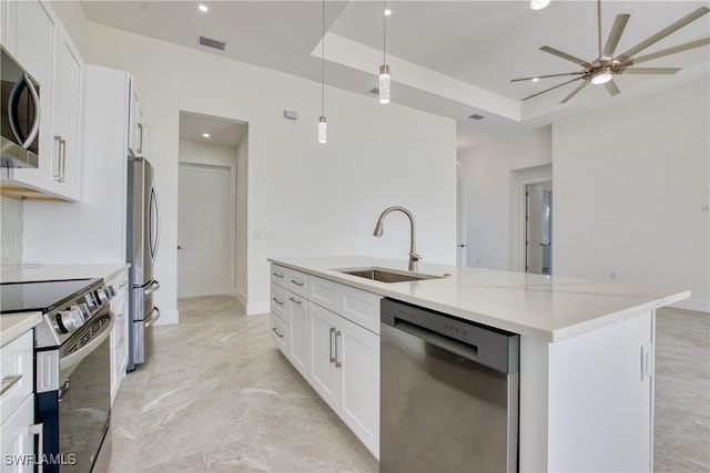 kitchen with stainless steel appliances, sink, a center island with sink, white cabinetry, and hanging light fixtures