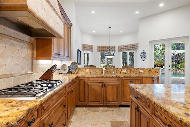 kitchen featuring custom exhaust hood, sink, hanging light fixtures, kitchen peninsula, and stainless steel gas cooktop