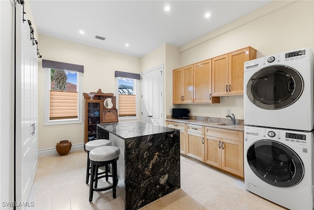 washroom with sink, light tile patterned floors, cabinets, and stacked washer / drying machine