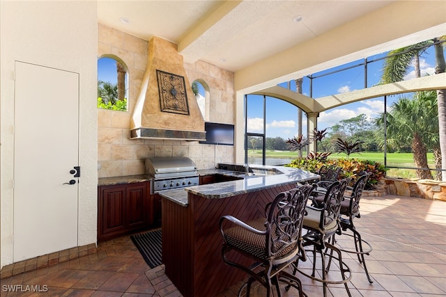 view of patio featuring an outdoor kitchen, a bar, and grilling area