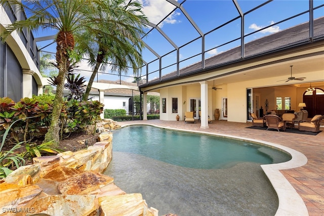 view of swimming pool featuring outdoor lounge area, ceiling fan, a patio area, and glass enclosure