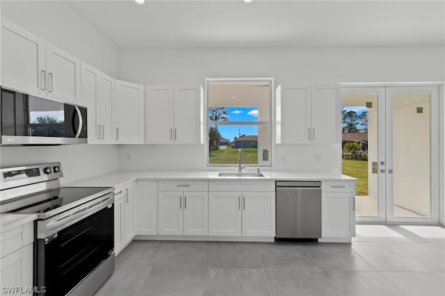 kitchen with appliances with stainless steel finishes, white cabinets, light tile patterned floors, and sink