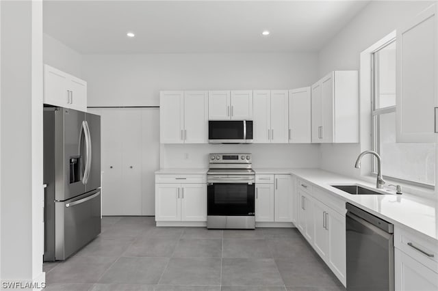 kitchen with sink, stainless steel appliances, white cabinetry, and light tile patterned floors