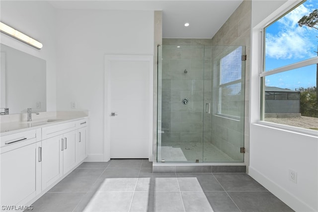 bathroom with a wealth of natural light, tile patterned flooring, vanity, and a shower with shower door