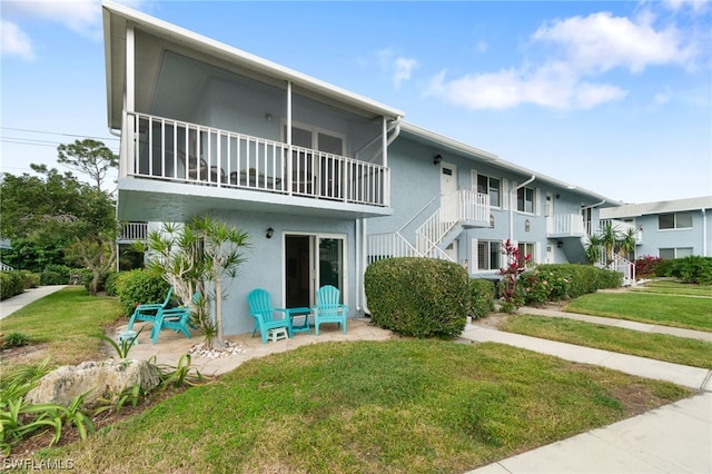 view of front facade featuring a balcony and a front lawn