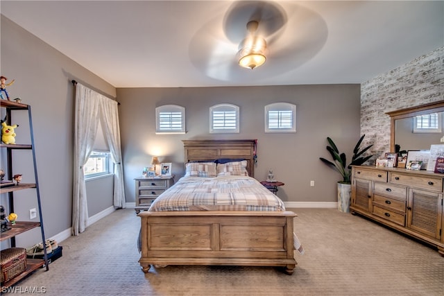 bedroom featuring light colored carpet, ceiling fan, and multiple windows