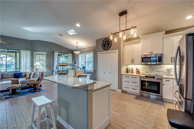 kitchen featuring white cabinets, stainless steel appliances, and decorative light fixtures