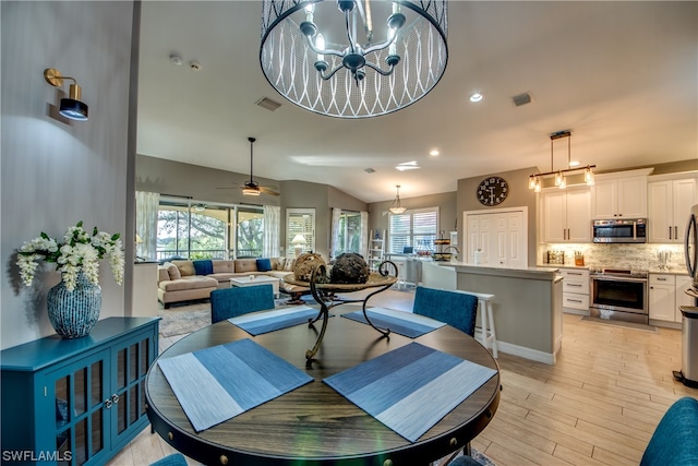 dining space with a healthy amount of sunlight, light hardwood / wood-style floors, and ceiling fan with notable chandelier