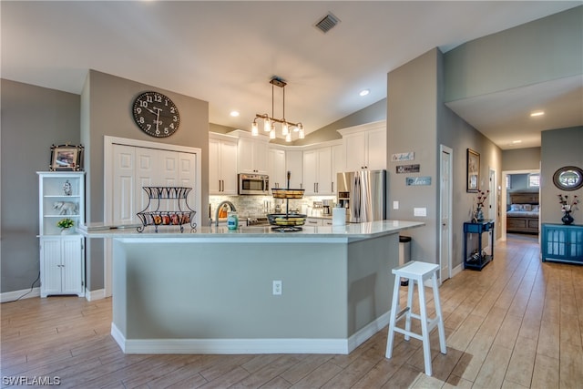 kitchen with white cabinetry, hanging light fixtures, a kitchen breakfast bar, a notable chandelier, and appliances with stainless steel finishes