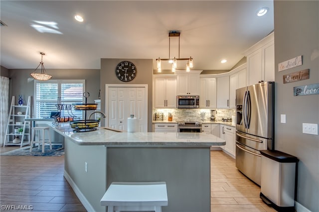 kitchen featuring white cabinets, appliances with stainless steel finishes, and pendant lighting