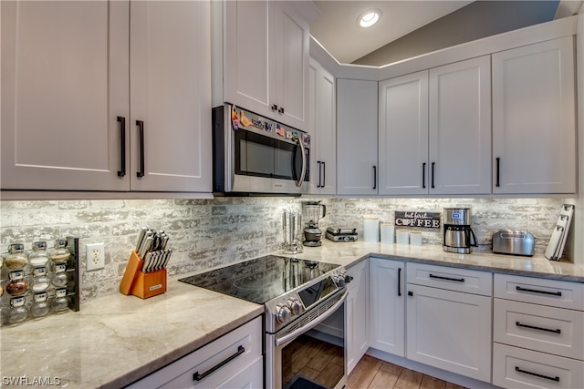 kitchen featuring white cabinetry, backsplash, vaulted ceiling, and stainless steel appliances