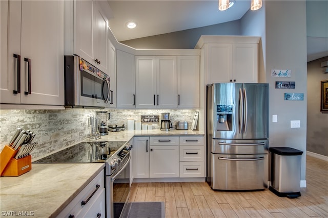 kitchen with white cabinets, backsplash, light hardwood / wood-style floors, stainless steel appliances, and vaulted ceiling