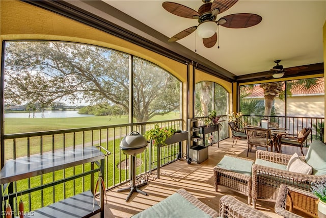 sunroom with a water view and ceiling fan