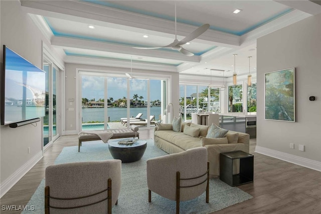 living room with crown molding, hardwood / wood-style floors, a water view, and a healthy amount of sunlight