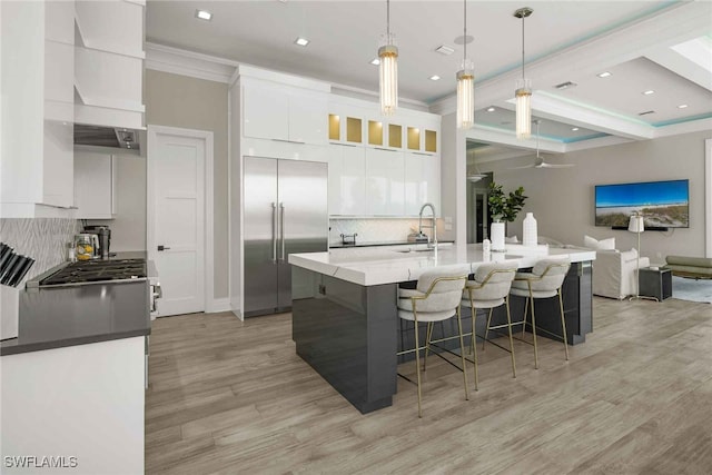 kitchen featuring pendant lighting, light hardwood / wood-style floors, premium appliances, and white cabinetry