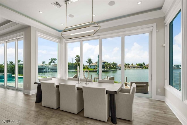 sunroom featuring a water view and a chandelier