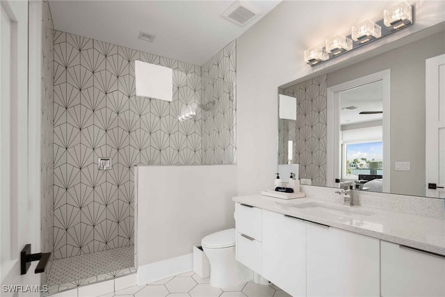 bathroom with vanity, tile patterned floors, toilet, and tiled shower