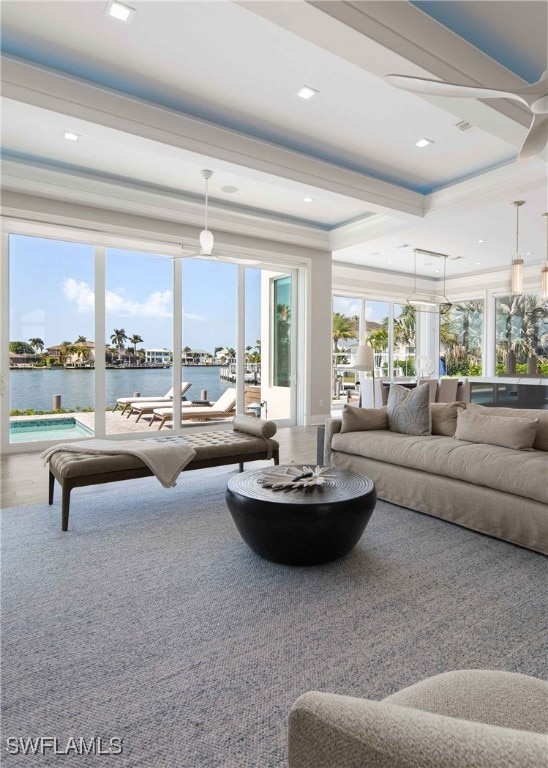 carpeted living room with a water view and crown molding