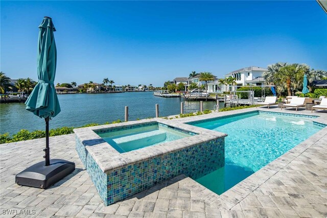 view of pool with an in ground hot tub, a water view, and a patio area