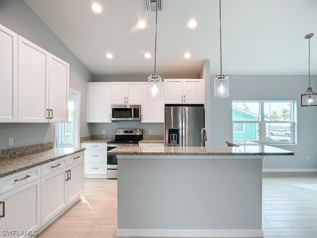 kitchen featuring a kitchen island with sink, plenty of natural light, decorative light fixtures, and stainless steel appliances