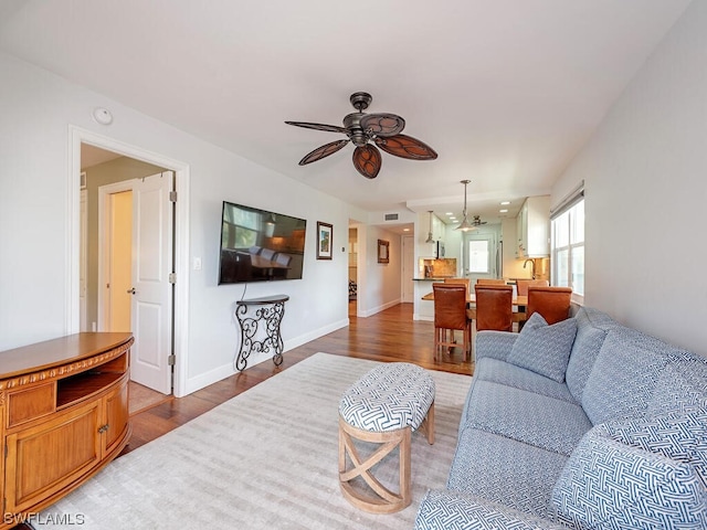 living room with dark hardwood / wood-style flooring and ceiling fan with notable chandelier