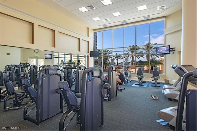 workout area with dark carpet and a drop ceiling