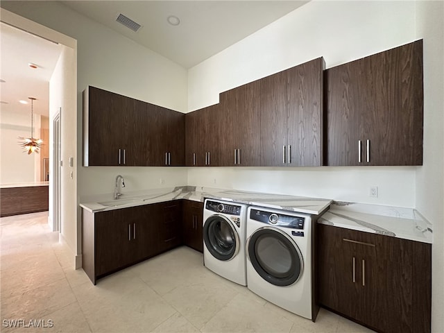 laundry area with light tile patterned floors, independent washer and dryer, cabinets, and sink