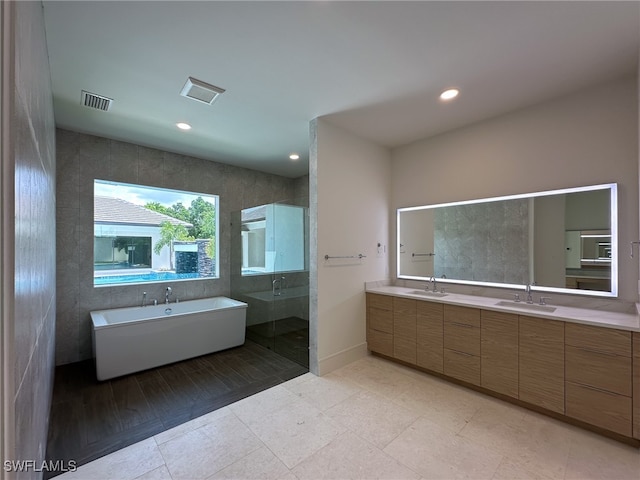 bathroom with tile patterned floors, tile walls, independent shower and bath, and vanity