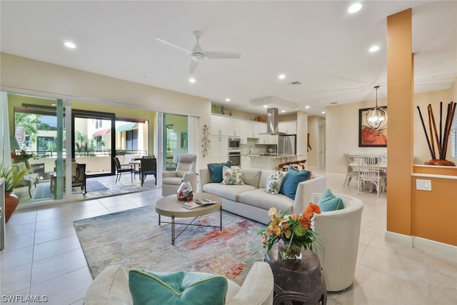 tiled living room with ceiling fan with notable chandelier