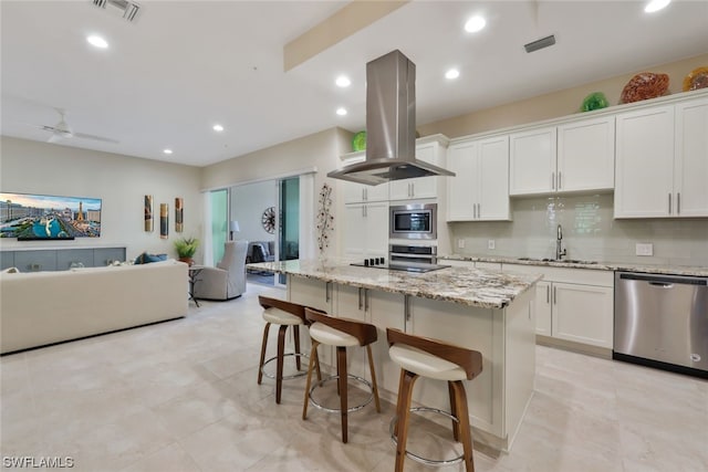 kitchen featuring island exhaust hood, a center island, stainless steel appliances, and white cabinetry