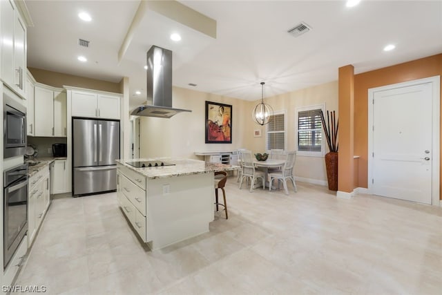 kitchen with island exhaust hood, appliances with stainless steel finishes, decorative light fixtures, white cabinets, and a center island