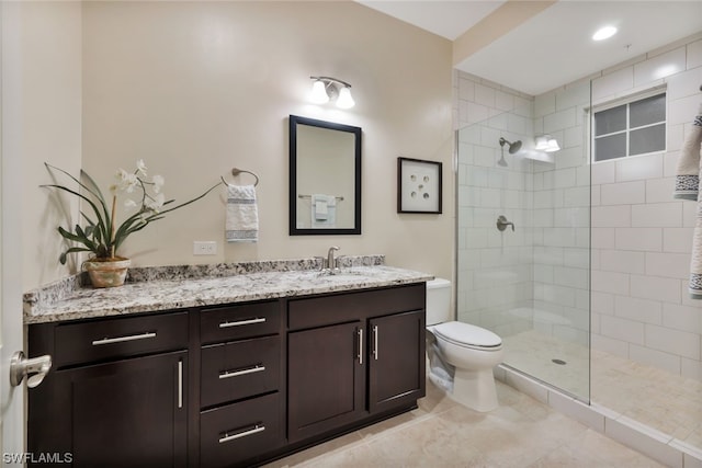 bathroom featuring tile patterned floors, toilet, vanity, and tiled shower