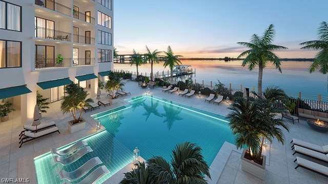 pool at dusk featuring a patio and a water view