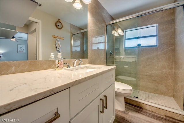 bathroom with toilet, ceiling fan, a shower with shower door, wood-type flooring, and large vanity