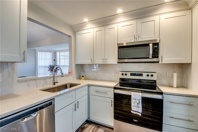 kitchen with sink, light stone counters, backsplash, stainless steel appliances, and white cabinetry