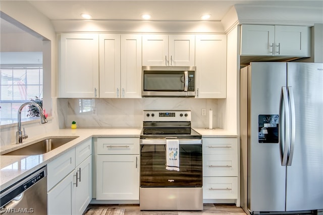 kitchen with backsplash, white cabinetry, appliances with stainless steel finishes, and sink