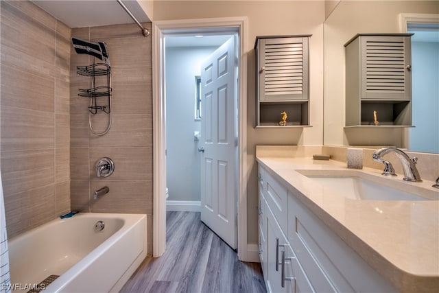 full bathroom featuring large vanity, toilet, wood-type flooring, and tiled shower / bath