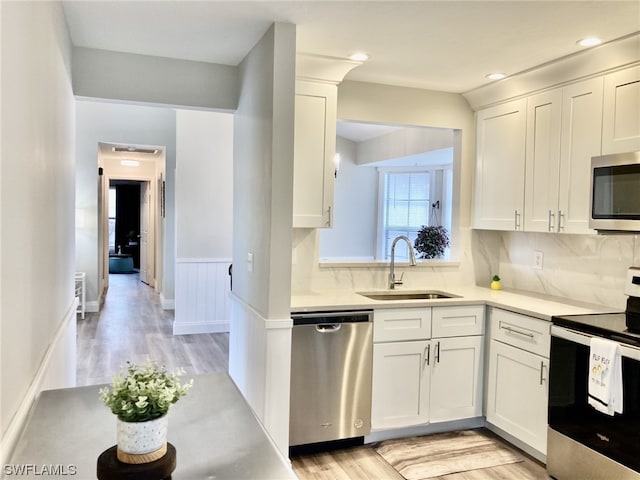 kitchen with white cabinetry, light hardwood / wood-style flooring, appliances with stainless steel finishes, and sink